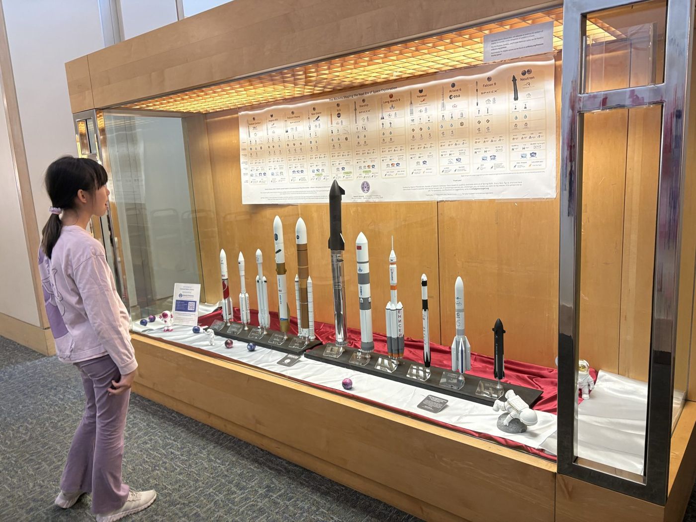 A young girl gazing up at the rocket models