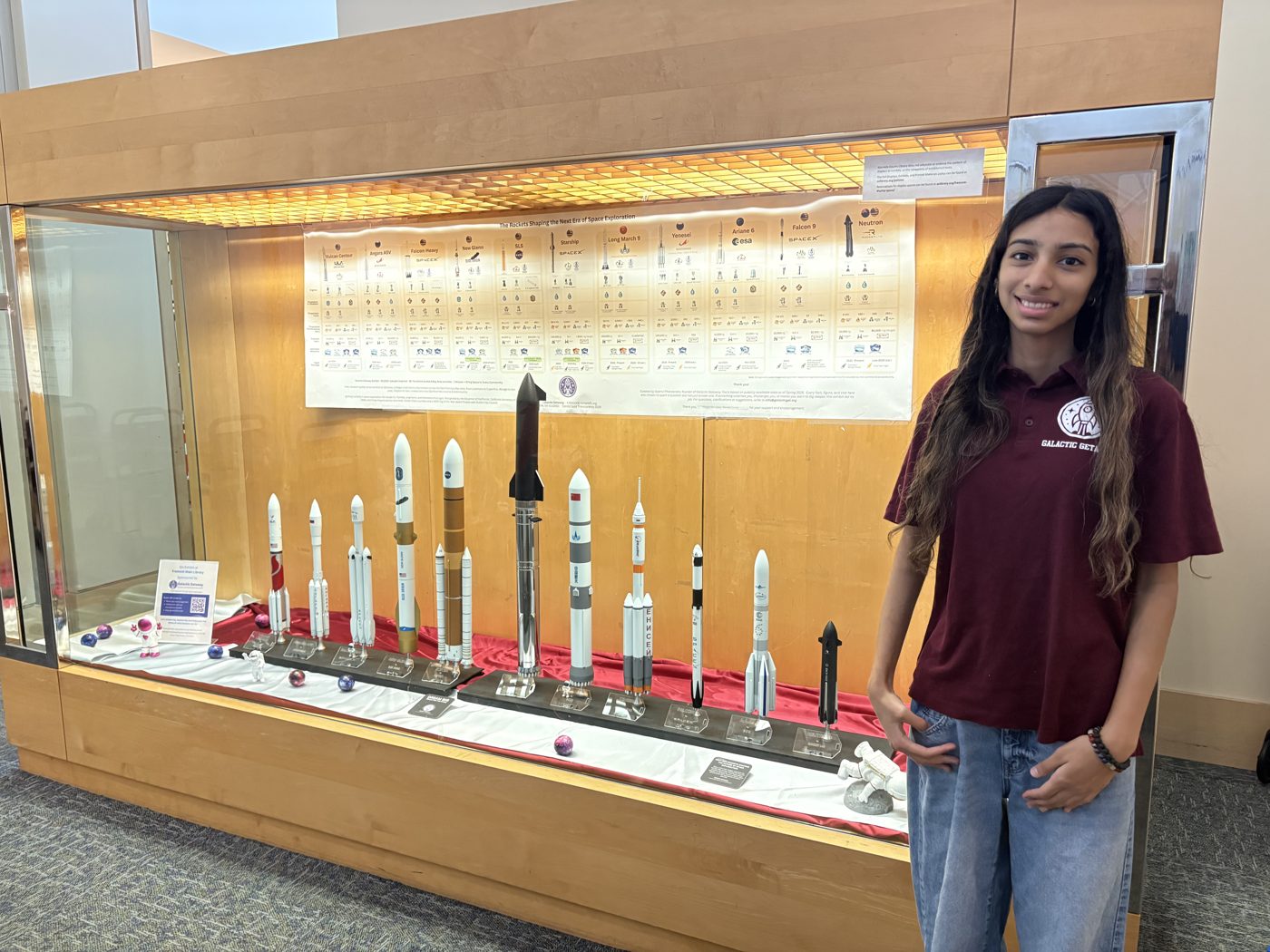 Saanvi Phaneendra standing beside the Galactic Getaway rocket exhibit at Fremont Main Library