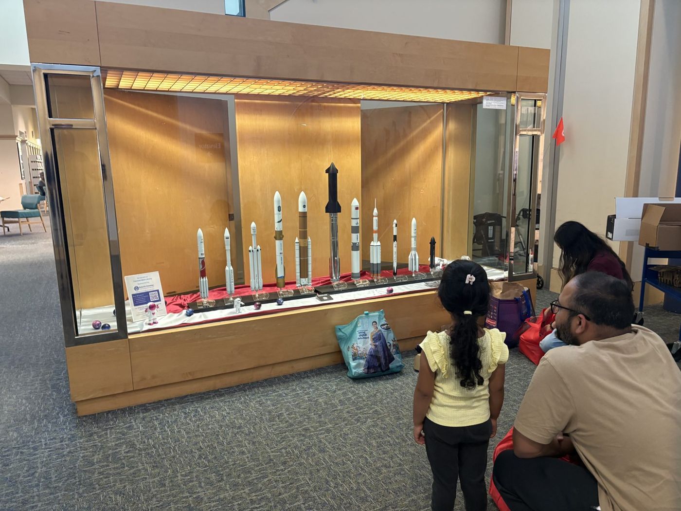 A young girl and her father looking at the rocket models together