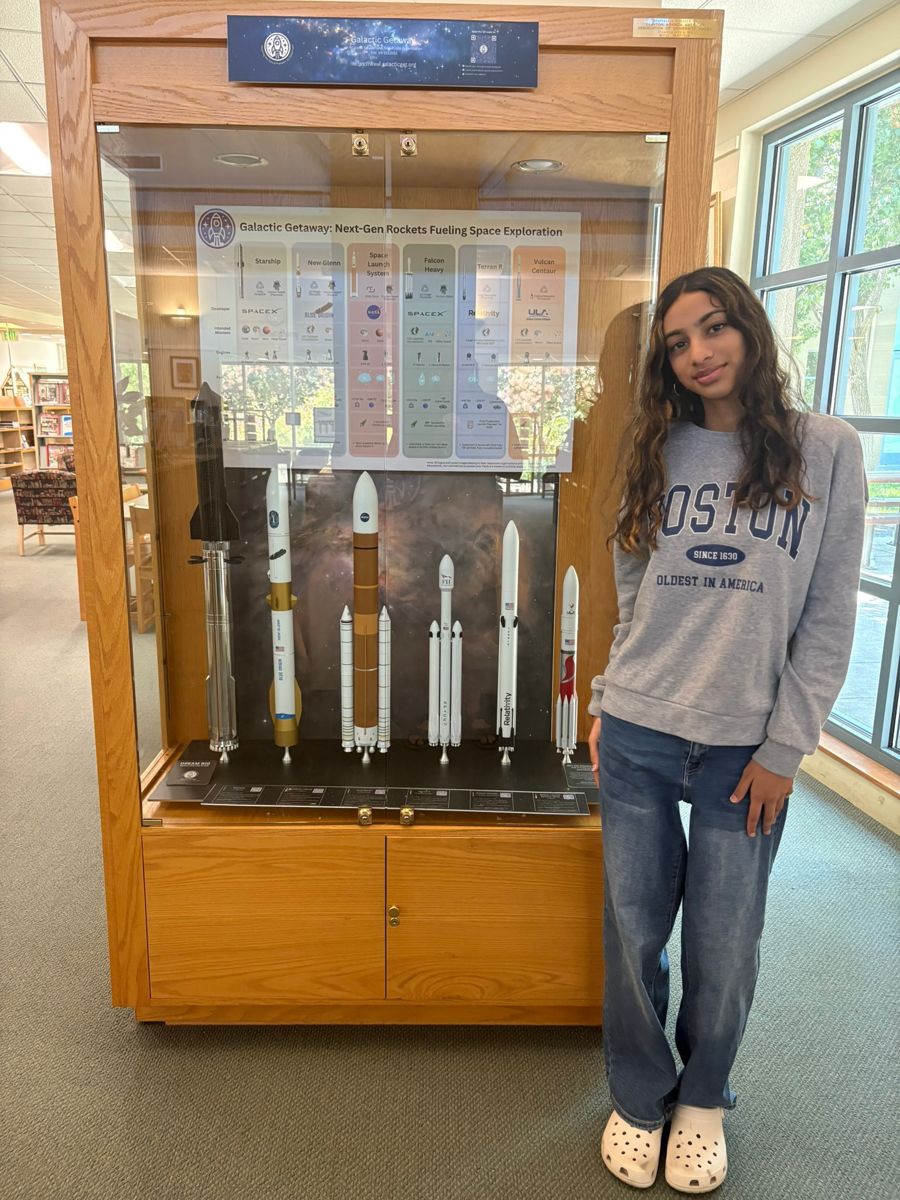 Saanvi Phaneendra with a partner librarian beside a rocket display